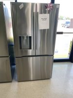 Stainless steel LG refrigerator with freezer drawers, water dispenser on left door; sale price sign on right door reading $1550.00