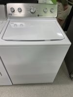 White top-load washing machine with a stainless control panel and circular knobs on the back panel