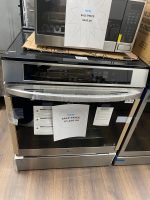 Stacked stainless steel LG oven and microwave with sale-price signs reading $1,250 and $495, taped cardboard around.