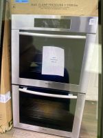 Stainless steel built-in oven in packaging with a sale sticker on the door area.