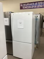 White side-by-side refrigerator with sale price tag reading $375 visible on the front; other appliance with $650 tag nearby in a showroom setting.