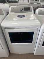Front-loading white washing machine on display in a store with a sale sign on its lid area.