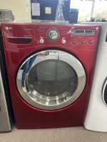 Red front-loading washing machine on display, with circular chrome door and control panel on top right.