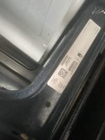 Close-up of a car door jamb with a white sticker showing a barcode and a QR code on the frame.
