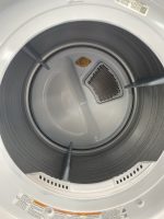 Interior of a front-loading clothes dryer drum with lint screen and warning labels along the rim