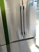 Stainless steel LG side-by-side refrigerator with vertical handles and a small blue sticky note on the right door.