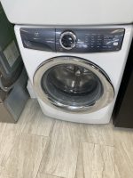 Front-loading Electrolux washing machine with a circular metal door and dark control panel, in a showroom.
