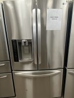 Stainless steel LG French-door refrigerator with built-in water/ice dispenser on the left door and a bottom freezer drawer; white sale sign taped on right door shows $595.00