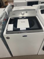 Maytag top-load washing machine with its lid open in a showroom; a sale price of $475.00 is placed inside the drum area.