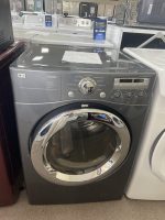img_5294-2 - Discount Appliances Front-loading LG Tromm washing machine in a showroom, with other appliances on display behind it.