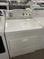 Front view of a white top-loading washing machine with a circular dial and a sale price tag showing $225 on the lid in a showroom.