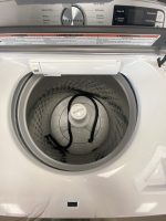 Front-loading washing machine with door open, inner drum visible and central agitator (Maytag) inside.