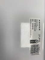 Close-up of a grey metal surface with a rectangular certification label containing text, a UL mark, and a QR code (label is rotated to the right).