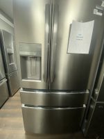 Stainless steel side-by-side refrigerator with external water dispenser and a sale price sign saying $1,595 on the door.
