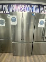 Stainless steel side-by-side refrigerators with sale signs stickered on doors in a showroom.