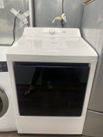 White LG front-loading washing machine on display in a showroom, with a 'NEW' sticker on the top panel and a sale tag nearby.