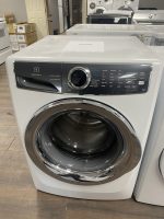 Front-loading Electrolux washing machine on display in a showroom with round door and dark control panel