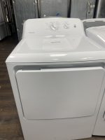 White top-load washing machine with a control panel on the back and a sale-price sign placed on the lid in a showroom setting.