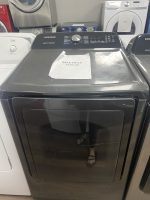 Samsung front-loading washing machine with aSale Price $295.00 tag on top; showroom reflection shows a person wearing sandals.