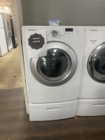 Samsung front-loading washer with a SALE sign showing $295.00 taped to the door; another price sign on the adjacent unit in a showroom.