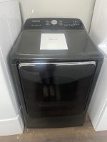 Black Samsung top-load washing machine with a sale price sheet placed on its lid in a laundry area.