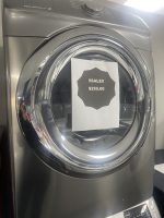 Front-loading washing machine with a sale sign reading '!!SALE!! $250.00' taped to the door.