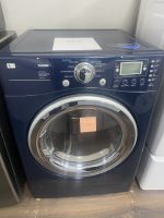Front-loading LG Tromm washing machine with digital control panel and circular door in a showroom setting
