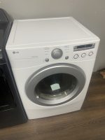 White LG front-loading washing machine with a large circular door and control panel on the right, labeled Sensor Dry, in a showroom setting.
