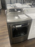 Front-loading silver washing machine on a showroom floor with a sale price sheet on its lid