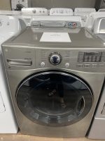 Front-loading LG washing machine (Sensor Dry) in a showroom with other machines in the background, stainless finish.