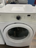 White front-loading washing machine on display with a sale flyer on its lid in a showroom.