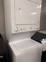 Stacked white washer and dryer with control panel and knobs visible at the front top.