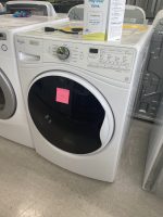 3ace2664-22bb-40f9-ad51-722c944cef8f-10075-0000034b67fd6587_file - Discount Appliances White front-loading washing machine in a showroom, pink sticky note on the door.