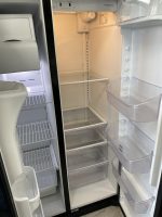 Open refrigerator interior with empty shelves and clear door bins, showing white interior and transparent door drawers.
