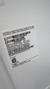 Close-up of a white appliance label with black text and a barcode, showing brand and installation/specification details (Electrolux).