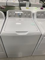 Close-up of a white GE top-load washing machine control panel with multiple dials in a showroom store display