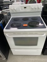 White freestanding electric range with four coil burners and a glass-ceramic cooktop in a showroom setting, showing the control panel above the oven door.
