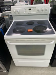 White freestanding electric range with four coil burners and a glass-ceramic cooktop in a showroom setting, showing the control panel above the oven door.