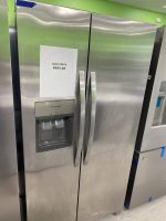 e08a8270-e1ba-4f2d-bda2-c3ec6825a964-40418-00000566858220d0_file - Discount Appliances Sale price sign on a stainless steel, side-by-side refrigerator: 'SALE PRICE $695.00' taped to the left door, with a green wall in the background.