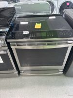 e4147973-9b6f-4a90-81b4-525ca3493039-4829-00000219918a7f50_file - Discount Appliances Stainless steel electric range with a glass-ceramic cooktop and a sticky note on the surface in a showroom setting