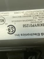 Close-up of a white label on a gray surface, showing the NSF certification mark and upside-down text including 'MADE IN' information.