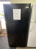 Black Frigidaire refrigerator with a white sale-sign taped to the door showing 'SALE PRICE $295' in a starburst outline.