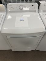 Top-loading LG washing machine with a sale price sheet inside the drum showing $595.00