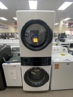 Tall Electrolux front-loading washer on display in a showroom with other appliances nearby.