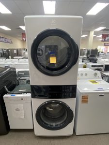 Tall Electrolux front-loading washer on display in a showroom with other appliances nearby.