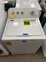 White top-load washing machine in a showroom, with control panel displaying wash options and an energy guide sticker on the lid's surface.