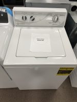 White top-loading washing machine in a store, with a sale price note reading $995.00 on the lid.