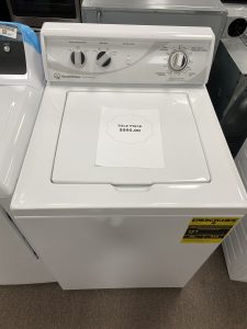 White top-loading washing machine in a store, with a sale price note reading $995.00 on the lid.