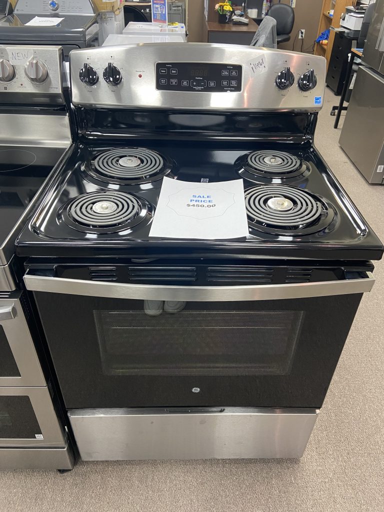 Black GE electric range with four coil burners in a showroom; sale price sheet resting on the cooktop.