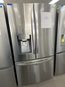Stainless steel LG French-door refrigerator on display with a sale price card reading $1,300.00 attached to the door